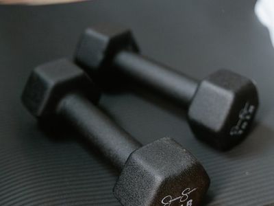 Dumbbells lying on a grey mat in a gym.